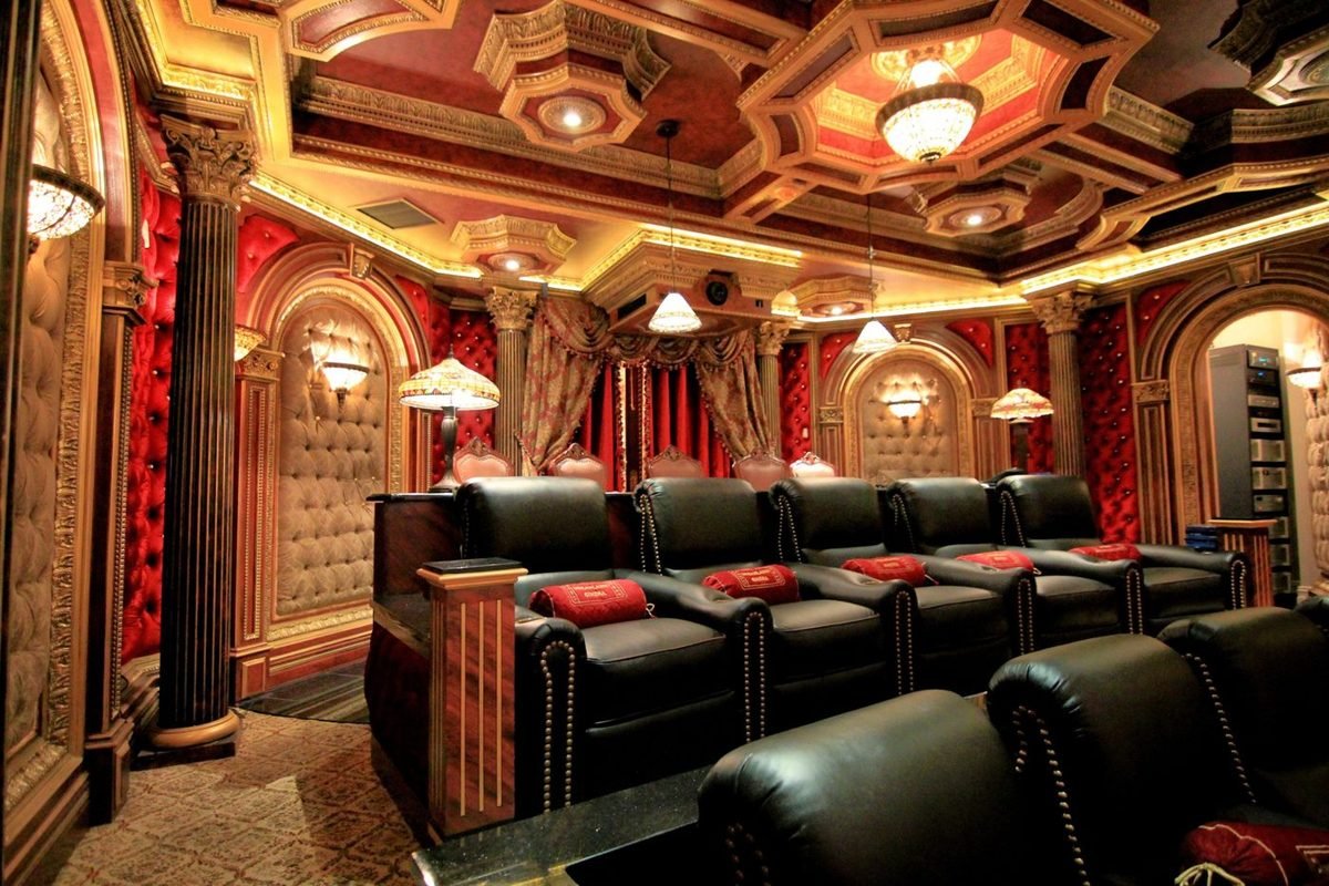 Ornate red and gold theater with Corinthian columns and black recliners